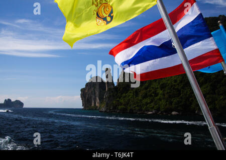 Ankommen auf tropischen Insel Ko Phi Phi mit der Fähre von Phuket - in der Nähe von Thai flag Waving vom Boot mit felsigen Küste, Thailand Stockfoto