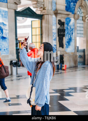 Porto, Portugal - April 29, 2019: Asiatische touristische Bilder im historischen Bahnhof Sao Bento in Porto, Portugal. Wand ist in b Stockfoto