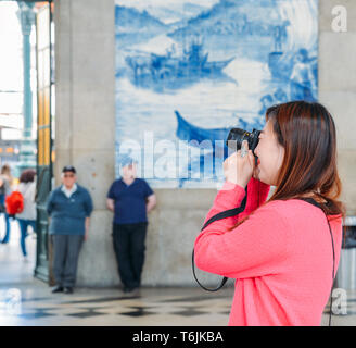 Porto, Portugal - April 29, 2019: Asiatische touristische Bilder im historischen Bahnhof Sao Bento in Porto, Portugal. Wand ist in b Stockfoto