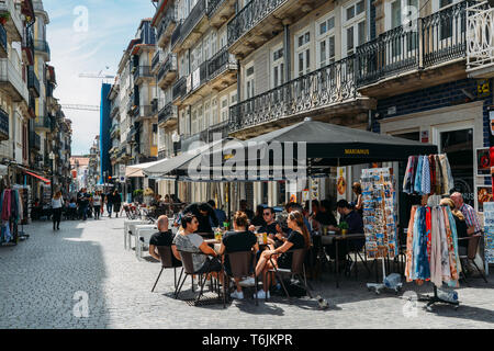 Porto, Portugal - April 29, 2019: die Menschen sitzen in Straßencafés an einem sonnigen Nachmittag im historischen Zentrum von Porto - UNESCO-Welterbe Stockfoto