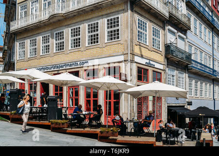 Porto, Portugal - April 29, 2019: die Menschen sitzen in Straßencafés an einem sonnigen Nachmittag im historischen Zentrum von Porto - UNESCO-Welterbe Stockfoto