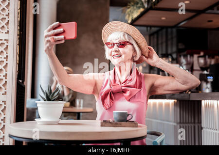 Übertragen von alte Frau tragen rosa Bluse und selfie Stockfoto