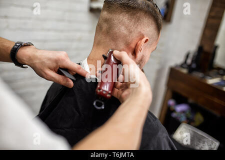 Brutaler Kerl in der modernen Friseur. Friseur Frisur macht ein Mann mit einem langen Bart. Master Friseur nicht Frisur mit Haarschneider Stockfoto