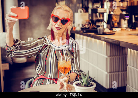 Moderne gut aussehende alte Dame in Sonnenbrille machen selfie Stockfoto