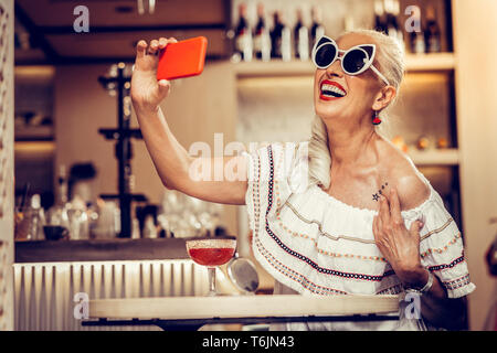 Lächelnd gut aussehender älterer Dame tragen weiße Sonnenbrille Stockfoto