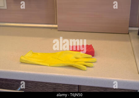 Reinigung der Arbeitsgeräte in der Küche Gummihandschuhe und Schwamm liegen auf die verschmutzte Oberfläche des Tisches, das Konzept der Sauberkeit Kopie Raum, la Licht aus Led Stockfoto