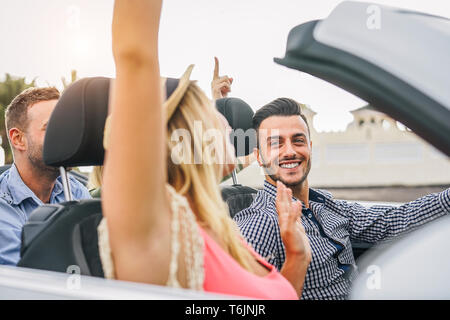 Gerne Freunde Spaß im Cabrio bei Sonnenuntergang im Urlaub - Junge reiche Leute die Party und Tanzen im Auto Cabrio während der Fahrt Stockfoto