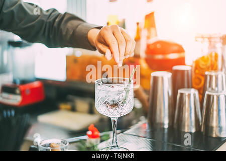 Barkeeper mixen einen Cocktail in einem Kristall Glas mit aromatischen Kräutern, die in der American Bar bei Sonnenuntergang - Barkeeper bei der Arbeit im Freien Stockfoto