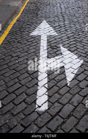 Gepflasterten Straße mit weißer Pfeil auf der Oberfläche lackiert, geradeaus oder rechts abbiegen, Konzept. Stockfoto