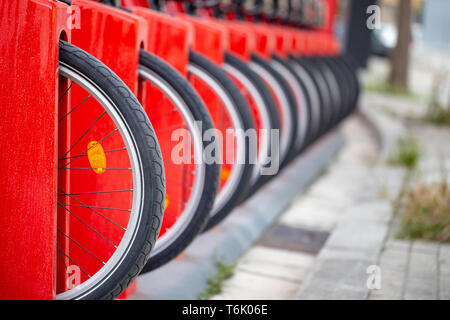 Viele Fahrrad in einer Reihe. Rote Fahrräder stehen auf einem Parkplatz zu mieten. Umweltfreundliches Transportkonzept. Stockfoto