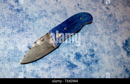 Damast Taschenmesser mit blauen Kamel Knochen Griff auf blauen und weißen Stoff angezeigt. Stockfoto