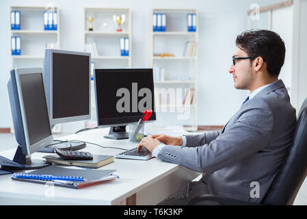 Unternehmer sitzen vor vielen Bildschirmen Stockfoto