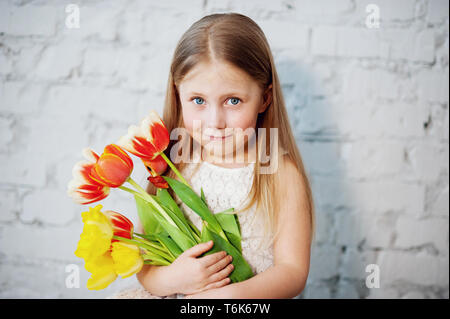 Mädchen, dass Tulpen in Händen. Bezaubernd lächelnde Mädchen mit Blumen für Ihre Mutter am Muttertag. Stockfoto