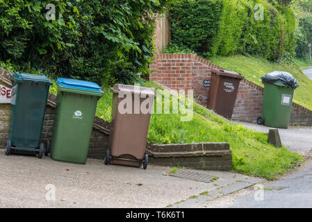 Gelb und grün Kunststoff wheelie bins Warten auf die Müllabfuhr aus bin Männer in einen Feldweg. Stockfoto