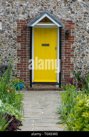 Ein hübsches Häuschen Tür in einem englischen Landschaft Dorf bemalten Gelb und einen Garten. Stockfoto