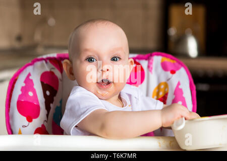 Baby ist 8 Monate und isst unabhängig. Der erste lure Baby. Das Baby mit blauen Augen nicht Gemüsebrei zu essen. mom Feeds von einem kleinen Kind' Stockfoto