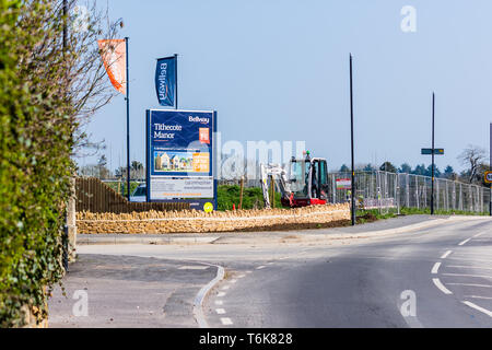 Ein Zeichen Fahnen von einer Entwicklung des neuen Gehäuses Tithecote Manor durch Bellway in Bradford on Avon Wiltshire mit Fechten einen kleinen digger Neben dem Schild. Stockfoto