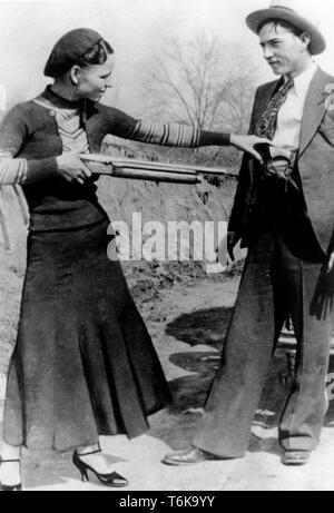 Bonnie und Clyde und Bonnie Parker soll spielerisch eine Pistole an Clyde Barrow. Bonnie Elizabeth Parker (1910-1934) und Clyde Chestnut Barrow (1909 - 1934) amerikanischer Verbrecher, die die mittleren Staaten der USA mit ihrer Bande während der Großen Depression reiste, raubt Banken und Geschäfte, und tötete mehrere Menschen Stockfoto