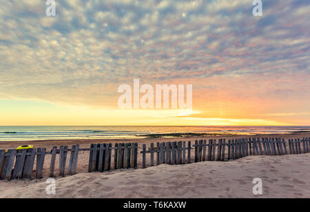 Zaun auf Sand strand bei Sonnenuntergang in Chipiona, Andalusien. Fußspuren im Sand. Ferienhäuser reisen Hintergrund Stockfoto