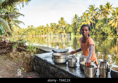 Nahaufnahme der lächelnden indischen Frau, die den Fluss Waschen von Töpfen und Pfannen am Rande des Dschungels in New Delhi, Indien Stockfoto