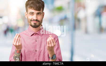 Jungen gutaussehenden Mann mit rosa Shirt über isolierte Hintergrund tut, um Geld Geste mit der Hand und bittet für Gehaltszahlungen, Millionär Business Stockfoto