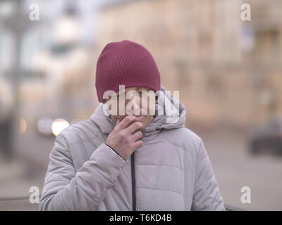 Porträt eines denkenden jungen Mann in einem Hut auf einem unscharfen Hintergrund der Straße Stockfoto