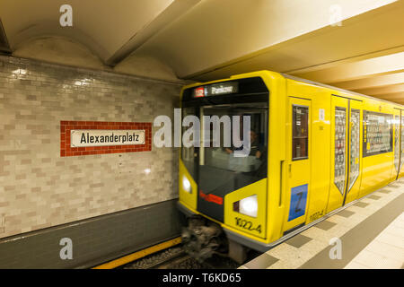 Alte Zeichen der Alexanderplatz U-Bahn U-Bahn / U-Bahn Station auf eine Kachel Wand und gelbe U-Bahn Zug nähert sich in Berlin. Stockfoto