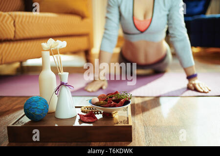 Nahaufnahme auf Fach mit duftenden Sachen für Aroma Yoga und passende Frau Yoga im Hintergrund bei modernen Haus. Stockfoto