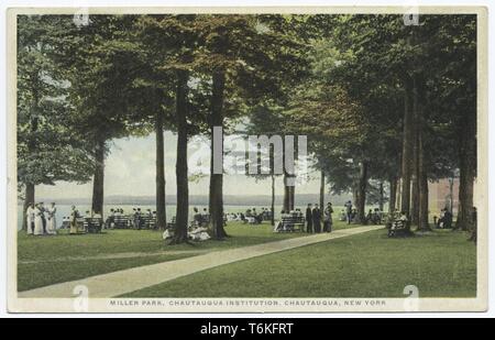 Postkarte mit einem Bild mit einer Ansicht von Menschen im Viktorianischen Sommer Bekleidung, stehen und sitzen auf Bänken unter hohen Bäumen, mit dem Chautauqua See in der Ferne sichtbar; in 'Miller Park", einer Fußgängerzone Park auf dem Gelände der Chautauqua Institution, einem historischen Resort und Bildung Komplex in Chautauqua, New York, 1914. Von der New York Public Library. () Stockfoto