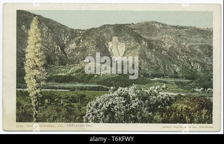 Postkarte mit einem Bild mit einer Ansicht der San Bernadino Bergen, mit der Helle, Quarz Umrisse der Pfeilspitze Wahrzeichen sichtbar auf dem Berg in der Mitte, und mit niedrigen, grüne Hügel, einem Körper von Wasser und Laub im Vordergrund; in der Nähe der Stadt San Bernardino gelegen, im Inland Empire, Kalifornien; durch die Detroit fotografische Begleitung, 1914 veröffentlicht. Von der New York Public Library. () Stockfoto