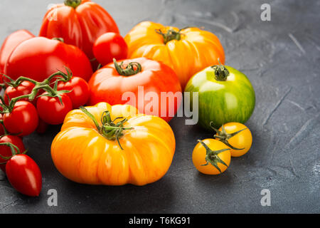 Auswahl an Bio große Erbstück und Kirschtomaten auf dunkelblau konkreten Hintergrund, selektiver Fokus Stockfoto