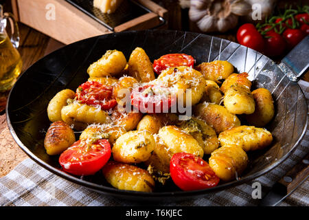 Gnocchi gebacken mit grünem Pesto, Kirschtomaten und Parmesan Stockfoto