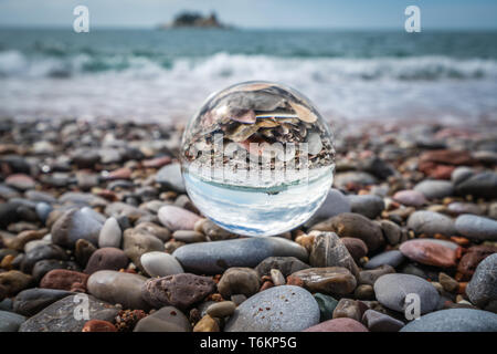 Strand Peebles in einem galss Ball wider Stockfoto