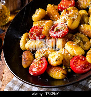 Gnocchi gebacken mit grünem Pesto, Kirschtomaten und Parmesan Stockfoto