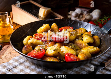 Gnocchi gebacken mit grünem Pesto, Kirschtomaten und Parmesan Stockfoto