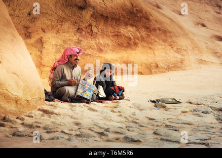 Beduinen Mann spielt traditionelle beduinische Rababa string Musikinstrumente mit Seinem Sohn in der antiken Stadt Petra, Jordanien Stockfoto