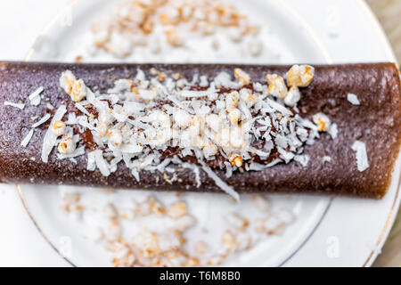 Makro Nahaufnahme von Schokolade krepp Nachspeise Wrap mit Puffreis, Kokos Flocken in der Trocknerflasche mit Bananen auf Blech Stockfoto