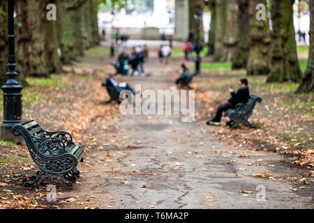 London, UK Gasse Pfad im Green Park in Westminster Querformat während der grünen Regenzeit nasse Herbst mit gefallenen Laub Blätter und Menschen sitzt auf der Bank Stockfoto