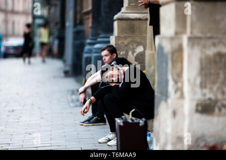 Lemberg, Ukraine - Juli 30, 2018: Ukrainische Stadt in der Altstadt Marktplatz mit goth Frau traurig Mädchen sitzen auf Bürgersteig in schwarzer Kleidung Stockfoto