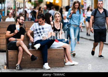 Lemberg, Ukraine - Juli 30, 2018: Historischen ukrainischen Polnischen Lvov Stadt bei Tag mit Freunden sitzen auf Bänken sprechen auf der Straße mit Kopfsteinpflaster in der Altstadt Stockfoto