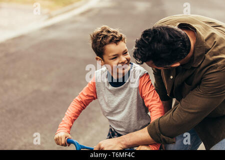 Vater, seinen Sohn auf einem Fahrrad. Menschen zu helfen, seinen Sohn zu Lernen, ein Fahrrad zu fahren. Stockfoto