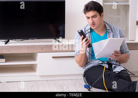 Mann, der versucht, defekte Fernseher zu reparieren Stockfoto