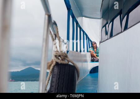 Surat Thai, Thailand - Januar 24, 2018: Touristen, die auf die Fähre nach Koh Samui und Koh Phangan Inseln. Mann sitzt auf dem Deck Stockfoto