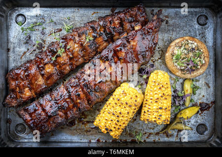 Barbecue Spare Ribs St Louis mit heißem Honig chili Marinade und Mais als Draufsicht in einem rustikalen Pfanne schneiden Stockfoto