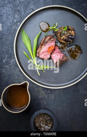 Traditionelle italienische Grill alter geschnittenes Rinderfilet mit Bärlauch und pioppinos als Draufsicht auf einer Platte Stockfoto
