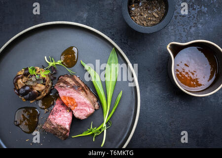 Traditionelle italienische Grill alter geschnittenes Rinderfilet mit Bärlauch und pioppinos als Draufsicht auf einem Teller mit Kopie Raum Stockfoto