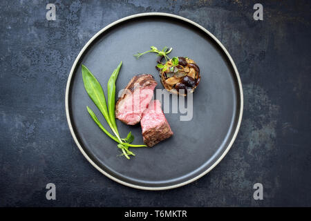 Traditionelle italienische Grill alter geschnittenes Rinderfilet mit Bärlauch und pioppinos als Draufsicht auf einem Teller mit Kopie Raum Stockfoto