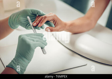 Professionell ausgebildete Nail master durch das Tragen von schützender Gummihandschuhe Stockfoto