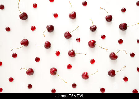 Süße reife Kirschen und Red Cherry Bonbons auf weißem Hintergrund verstreut. Stockfoto