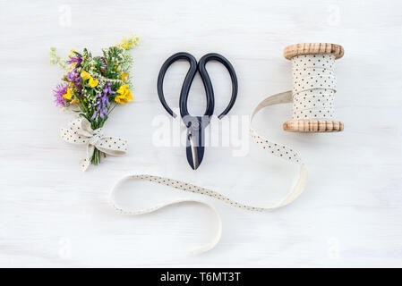 Blumenstrauß aus Wildblumen mit Jahrgang und Band schwarz Schere eingerichtet, auf weißem Holz- Hintergrund. Stockfoto